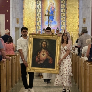QU students holding sacred heart portrait